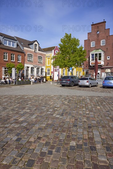 Restaurant and houses with colourful facades and a street of cobblestones in the harbour of Husum, Nordfriesland district, Schleswig-Holstein, Germany, Europe