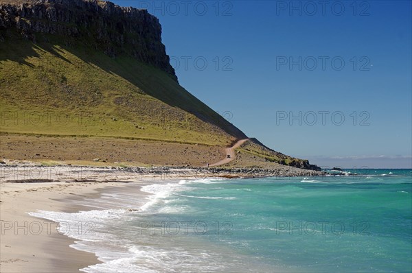 Lonely sandy beach and gravel track in front of vegetation-free mountains, Latrabjarg, Westfjords, Iceland, Europe