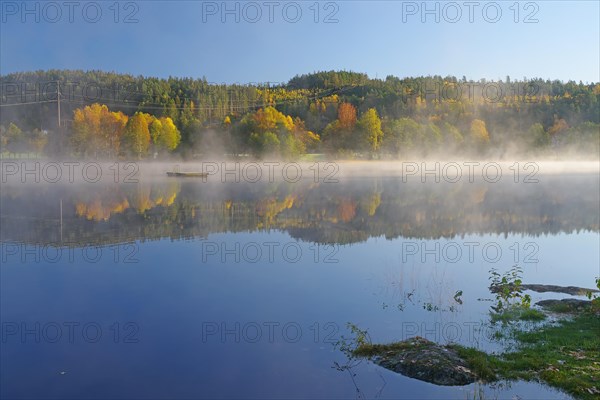 Sunrise and autumnal morning mist over a calm lake, foliage colouring, Bullaren, Bohuslaen. Sweden