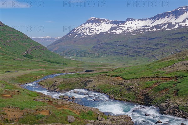 Water falls into a deeply incised valley framed by high mountains, ferry town, Seydisfjoerdur, East Iceland, Iceland, Europe