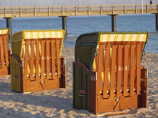 Beach chairs in the sunlight on the sandy beach, with sea and pier in the background, beach chairs in the morning light with blue sky by the sea, pier in the sea, Binz, Germany, Europe