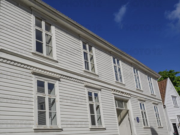 White wooden houses with many windows and red tiled roofs under a blue sky, white wooden houses with green trees and flowers against a blue sky, Stavanger, Norway, Europe