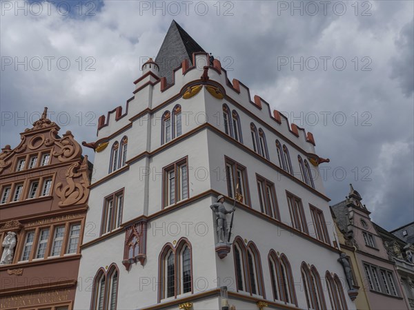 A historic gothic building with rich decoration under a cloudy sky, historic house fronts with a monument against an overcast sky, Trier, Germany, Europe