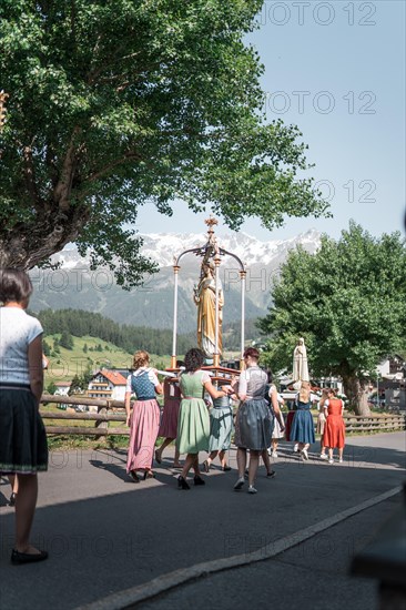 A procession with a statue of the Virgin Mary and traditionally dressed people. Nauders, Austria, Europe