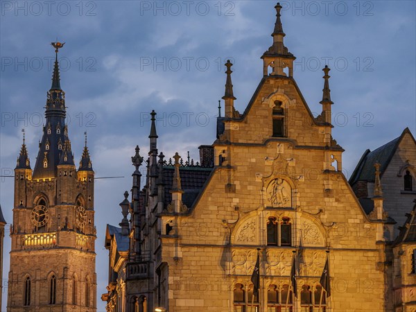Detailed gothic architecture and a church tower in a historic city at night, historic buildings with towers and lanterns at blue hour, gent, belgium