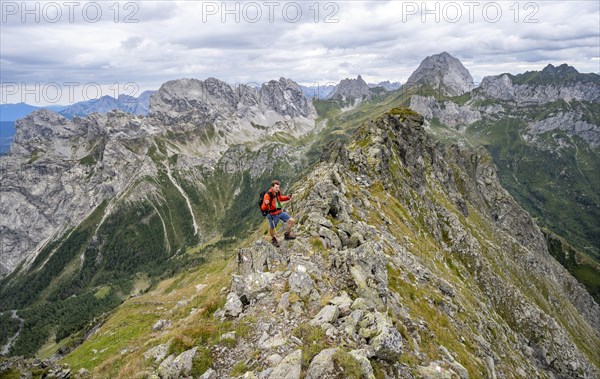 Mountaineer on a narrow rocky mountain path on a ridge, descent from the Raudenspitze, view into the Val Fleons valley with rocky mountain peaks, Carnic Main Ridge, Carnic Alps, Carinthia, Austria, Europe