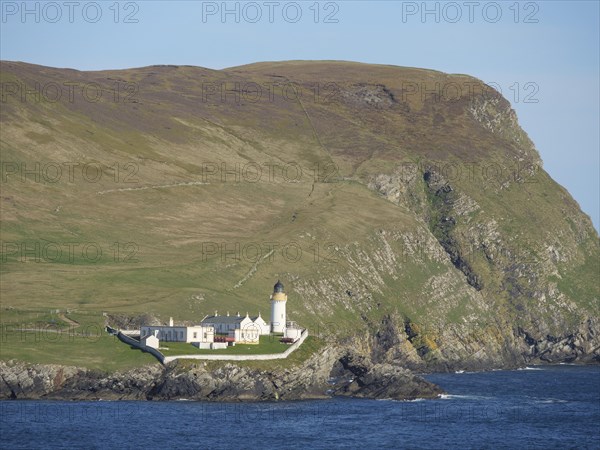 Lighthouse on a rocky coast, surrounded by green hills and blue sea under a clear sky, white lighthouse, on a rocky ground in the blue sea, surrounded by green fields, lerwick, shetland, Scotland, United Kingdom, Europe
