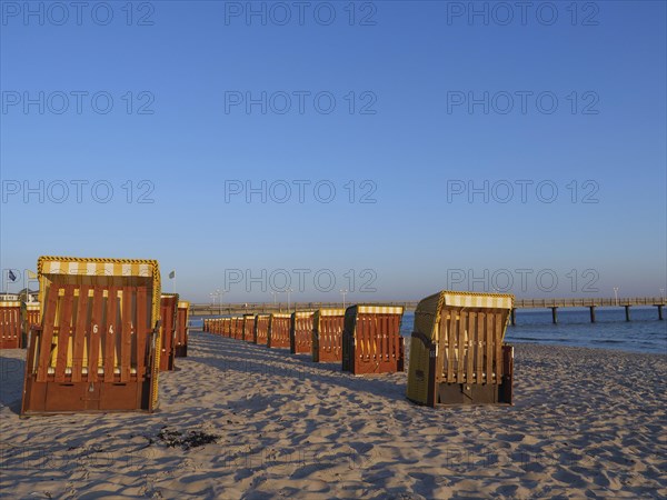Beach chairs on a sunny beach with blue sky and calm sea, in the background a pier, beach chairs in the morning light with blue sky by the sea, pier in the sea, Binz, Germany, Europe