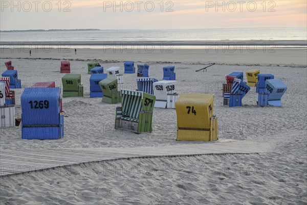 A cool beach evening with colourful beach chairs, a wooden walkway and a quiet atmosphere, lots of colourful beach chairs on a balmy summer evening by the sea, langeoog, germany