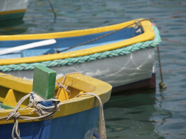 Close-up of a part of a yellow and blue fishing boat in the water, many colourful fishing boats in a harbour in the Mediterranean Sea, Marsaxlokk, malta