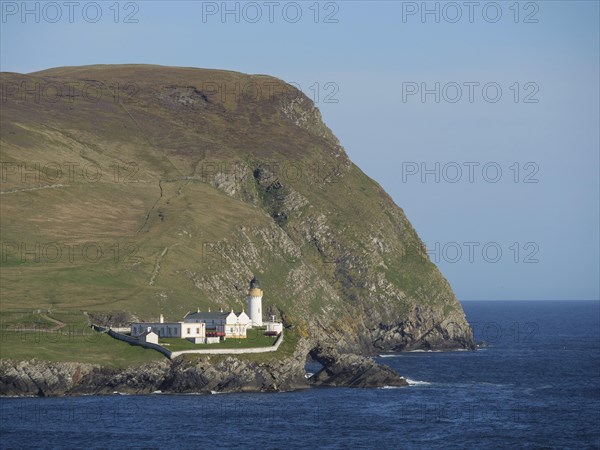 Lighthouse on a rocky coast, surrounded by green hills and blue sea under a clear sky, white lighthouse, on a rocky ground in the blue sea, surrounded by green fields, lerwick, shetland, Scotland, United Kingdom, Europe