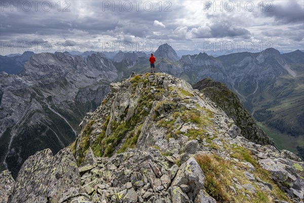 Mountaineer in front of a mountain landscape with rocky peaks, at the summit of the Raudenspitze or Monte Fleons, Carnic Main Ridge, Carnic Alps, Carinthia, Austria, Europe