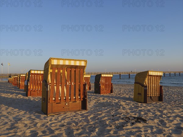 Beach chairs on the sandy beach illuminated by the evening sun, with a view of the sea and the pier, beach chairs in the morning light under a blue sky by the sea, pier in the sea, Binz, Germany, Europe