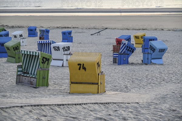 A quiet and relaxing beach evening with colourful beach chairs, a wooden walkway and soft sand, lots of colourful beach chairs on a balmy summer evening by the sea, langeoog, germany