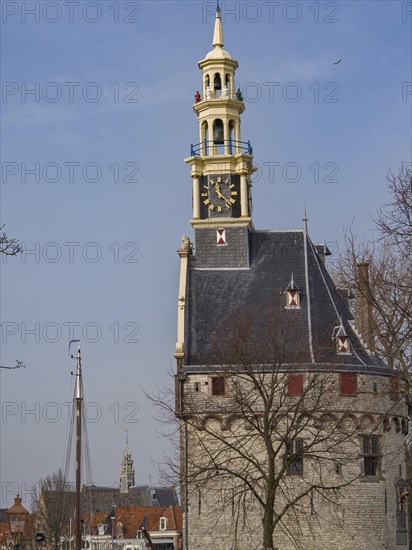 Historic clock tower with a view of the city and sailing boats against a blue sky, tower with a golden spire and a large clock against a blue sky, hoorn, the netherlands