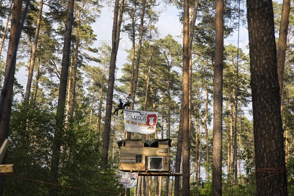 Two people swing above a tree house in the occupied section of the Tesla Stop forest. The occupation of the forest is intended to demonstrate against the imminent clearing for the planned expansion of the Tesla Gigafactory in Gruenheide. 11.05.2024