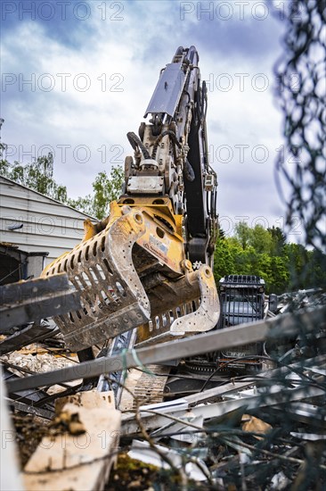 An excavator's metal tongs move rubble and debris in a construction site with green background, demolition, Saarbruecken, Germany, Europe