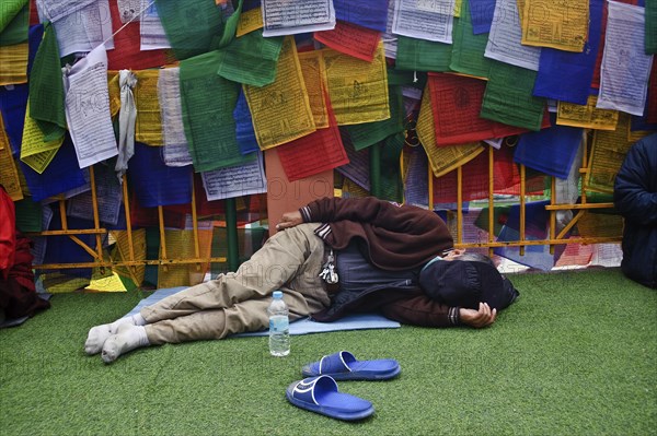 Asian buddhist pilgrim sleeping in the Mahabodhi temple complex, Bodhgaya, Bihar, India. The Mahabodhi temple marks the place where the Buddha has attained enlightenment. It is now a major pilgrimage centre for buddhists from all over the world