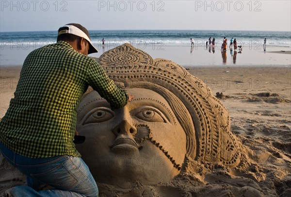 Sand artist sculpting a sand sculpture, sculpture representing the hindu goddess Lakshmi, beach at Puri, India, Asia
