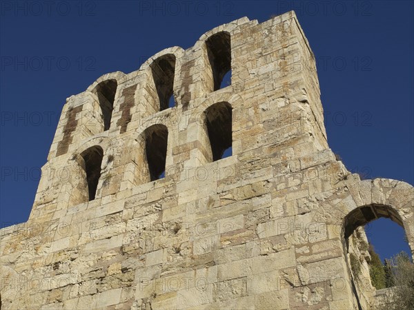 Ancient stone structure with several arches in front of blue sky, Ancient building with columns and trees on the Acropolis in Athens in front of blue sky, athens, greece