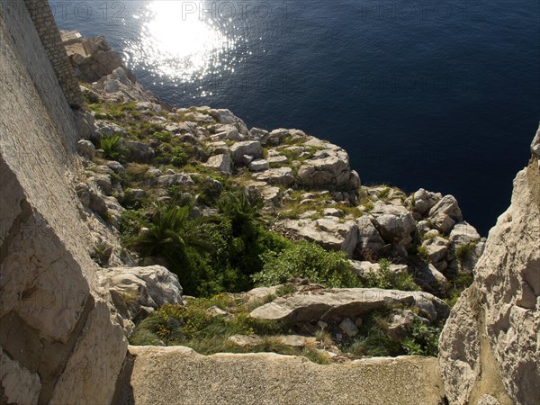 Rocky coast sloping into the sunny sea, the old town of Dubrovnik with historic houses, churches, red roofs and fortress walls, dubrovnik, coratia