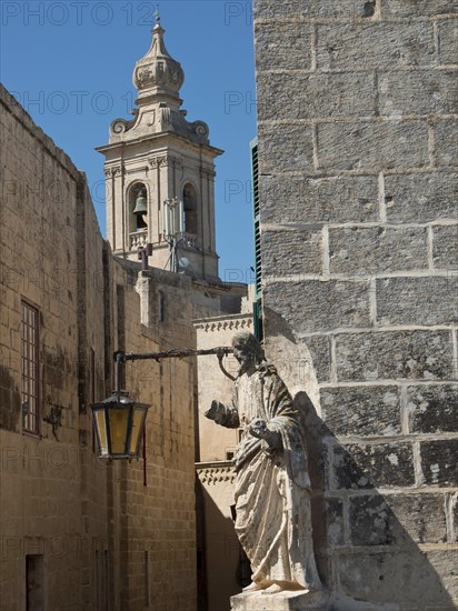 Street with historic architecture, sculpture and church tower in the background, the town of mdina on the island of malta with historic houses, colourful balconies, magnificent churches, mdina, Malta, Europe