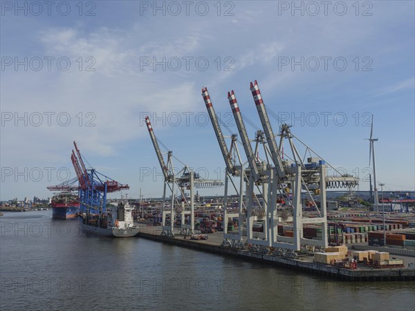 A view of an industrial harbour with several cranes, containers and a cargo ship at the quay, large cranes in a harbour, hmburg, germany