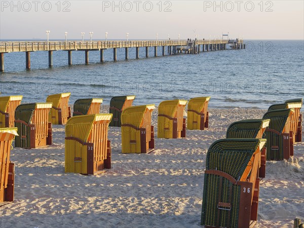 Beach chairs by a pier, illuminated by warm evening light, peaceful atmosphere, autumn atmosphere on the beach of Binz with trees beach chairs in the morning light, Binz, germany