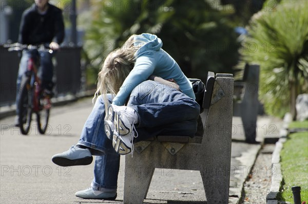 Couple Sleeping on a Bench and One on Bicycle in a Sunny Day on Walkway in Switzerland