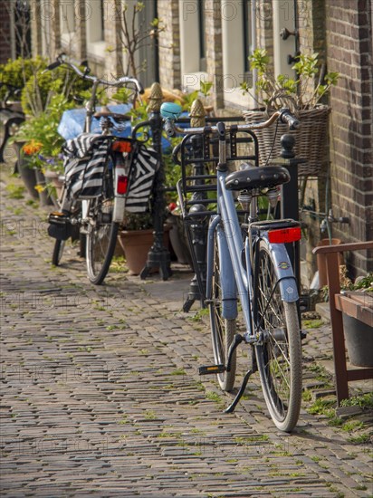 Bicycles parked in a quiet, cobbled street in the old town, historic houses in Hoorn and ships in the harbour, hoorn, the netherlands