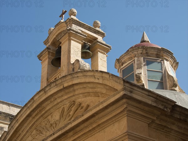 A building of an old church with bells and round windows under a blue sky, the town of mdina on the island of malta with historic houses, colourful balconies, magnificent churches, mdina, Malta, Europe