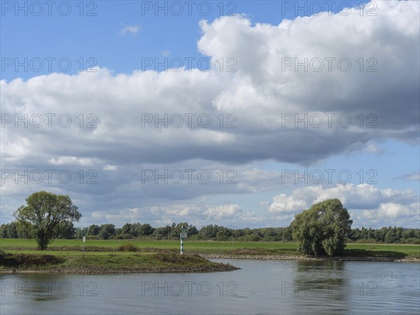 Calm river with big clouds and green landscape, white clouds over a calm river bank with trees, doesburg, Netherlands