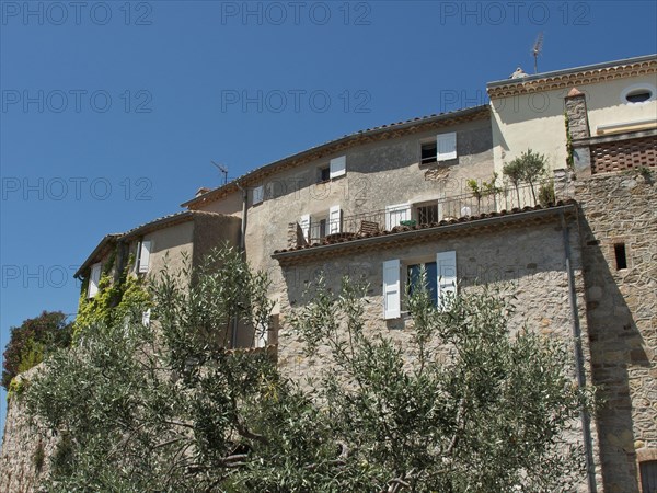 Rustic stone houses with white shutters and vegetation against a clear blue sky, Provence, le Castellet, France, Europe
