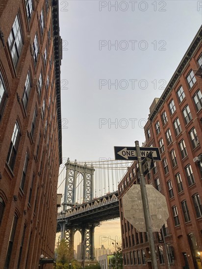 Bridge framed by tall red brick buildings with clearly visible street signs, new york from above with impressive skyscrapers and clouds in the sky, New york, USA, North America