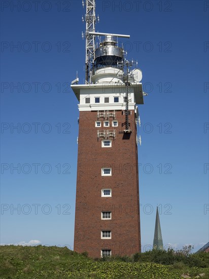 High brick lighthouse under blue sky with technical superstructures, Heligoland, Germany, Europe