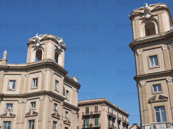 Two historic towers with beige facades under a clear sky, witnesses of classical architecture, palermo in sicily with an impressive cathedral, monuments and old houses with balconies, palm trees and flowers in italy, palermo, sicily