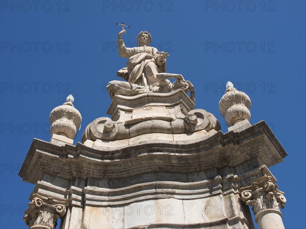 Detailed baroque statue with religious symbolism in front of a bright blue sky, palermo in sicily with an impressive cathedral, monuments and old houses with balconies, palm trees and flowers in italy, palermo, sicily