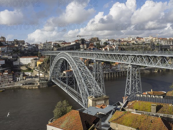 Steel bridge over a river in a historic city in sunny weather with clouds, spring in the old town of Porto on the Douro with historic houses, Porto, portugal