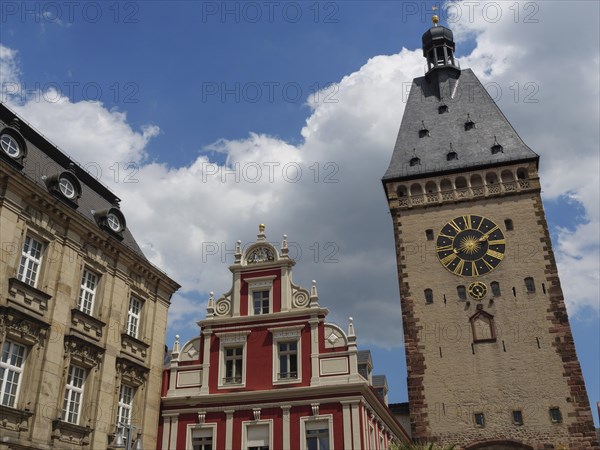 A clock tower and decorated building under a cloudy sky, tower with tower clock in front of historic houses, Speyer, Germany, Europe