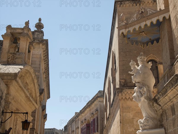 A street of historic buildings and statues under a blue sky, the town of mdina on the island of malta with historic houses, colourful balconies, magnificent churches, mdina, Malta, Europe