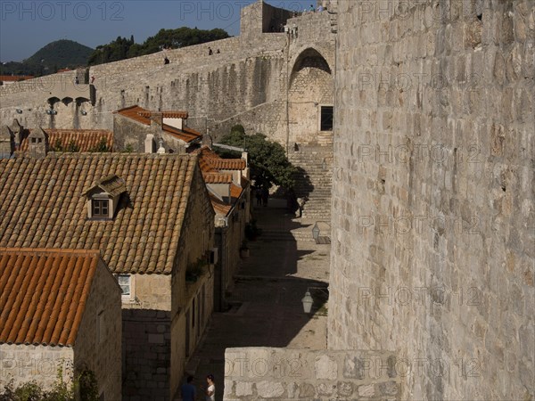 View of a medieval town with old stone buildings and tiled roofs lined by a historic wall, the old town of Dubrovnik with historic houses, churches, red roofs and fortress walls, dubrovnik, coratia