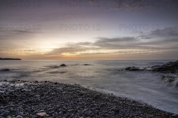 Sunrise with sea view in a lonely bay. rocky coast in warm colours. Landscape with a lava stone beach of Tarajalejo on Fuerteventura, Canary Islands, Spain, Europe