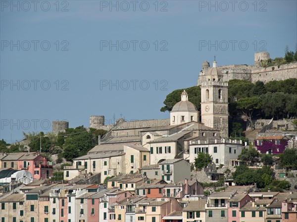 Church and fortress in a coastal town with colourful buildings in front of a wooded hill under a sunny sky, Bari, Italy, Europe