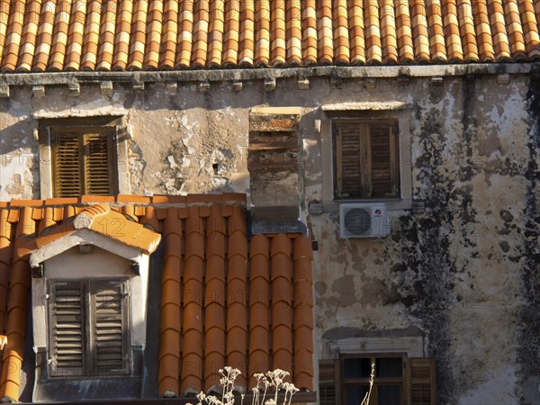 Old buildings with red tiled roofs and closed shutters, partially dilapidated facades, the old town of Dubrovnik with historic houses, churches, red roofs and fortress walls, dubrovnik, coratia