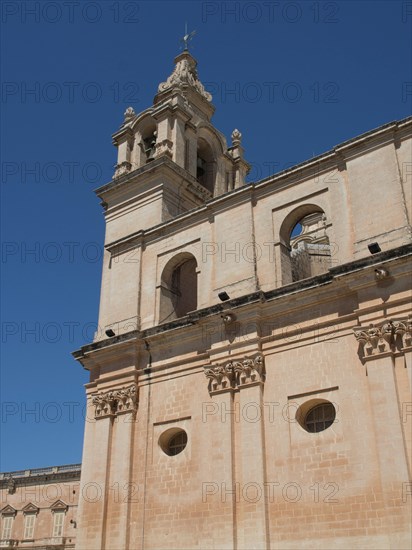 A tall church tower and sand-coloured buildings under a clear blue sky, the town of mdina on the island of malta with historic houses, colourful balconies, magnificent churches, mdina, Malta, Europe