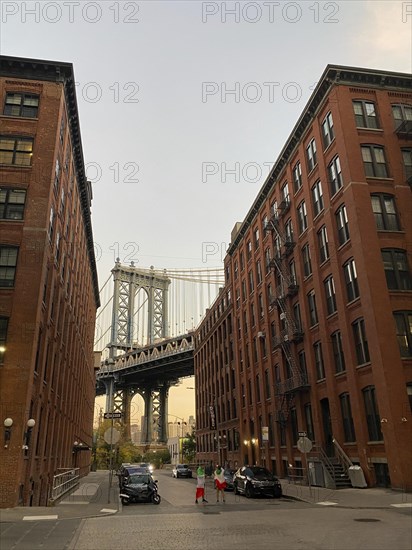 View of a famous bridge framed by brick buildings at dusk, new york from above with impressive skyscrapers and clouds in the sky, New york, USA, North America