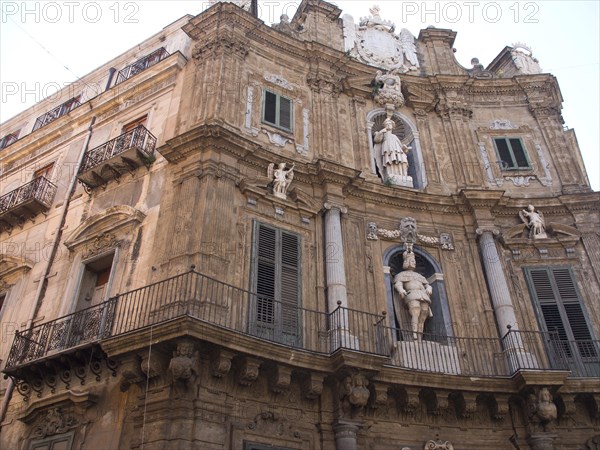 Baroque facade of a historic building with ornate sculptures and balconies, palermo in sicily with an impressive cathedral, monuments and old houses with balconies, palm trees and flowers in italy, palermo, sicily