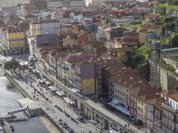 Riverside cityscape with colourful buildings, busy streets and people under a cloudy sky, spring in the old town of Porto on the Douro with historic houses, Porto, portugal