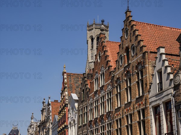 Detail of buildings with decorated towers and roof tiles under a clear sky, historic house facades in a medieval town by the river, Bruges, Belgium, Europe