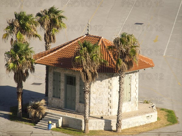 Small pavilion with red roof tiles surrounded by palm trees on an asphalted area, Ancient building with columns and trees on the Acropolis in Athens against a blue sky, athens, greece
